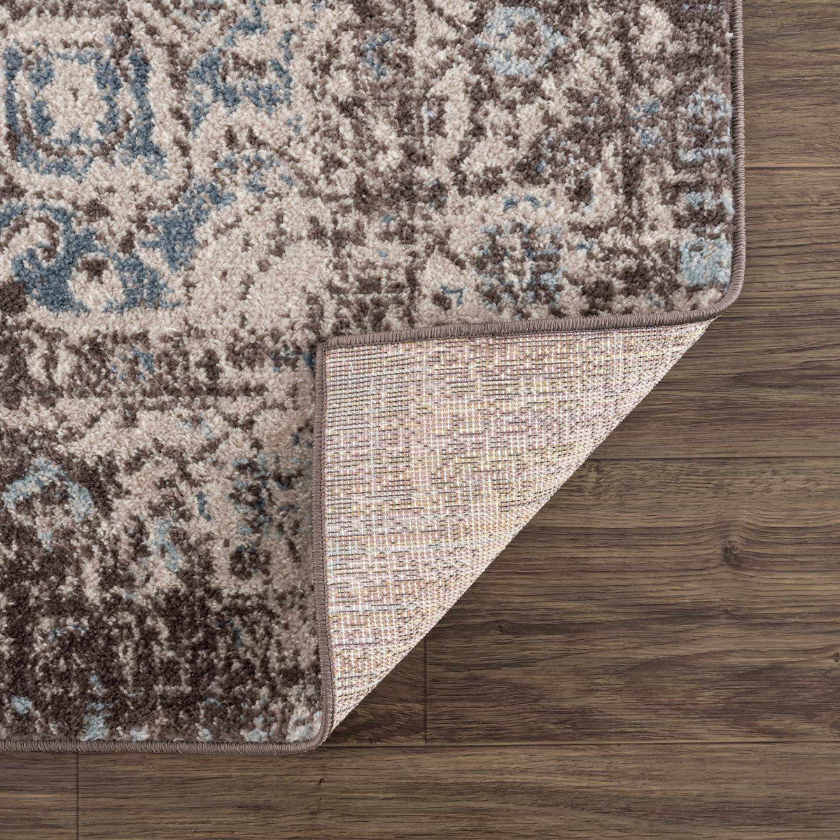Dark brown medallion area rug by Hauteloom with intricate pattern, folded to show detailed design and plush texture.