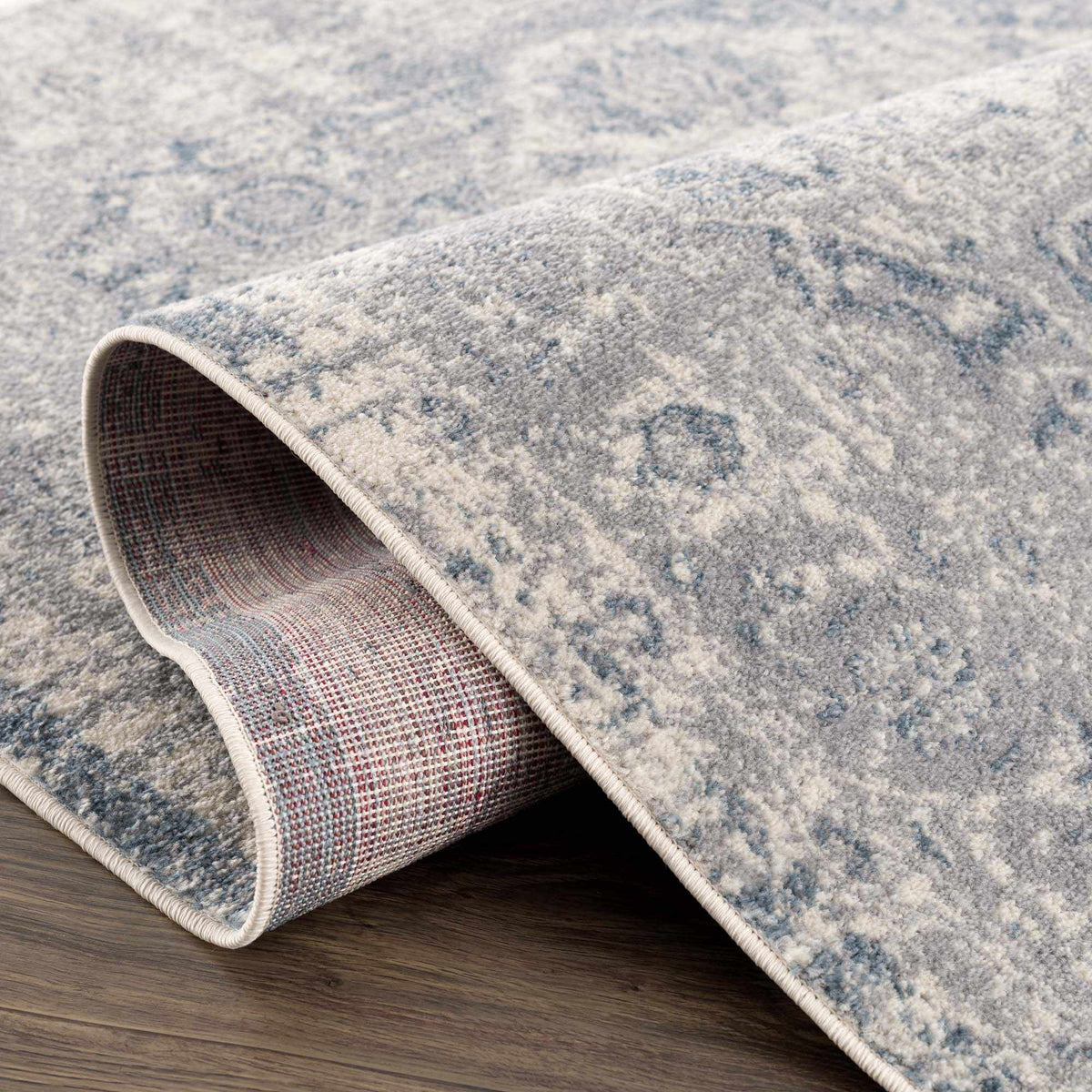 Hauteloom Peeta Gray Blue Medallion area rug with intricate medallion pattern on soft fabric, shown folded on a studio surface.