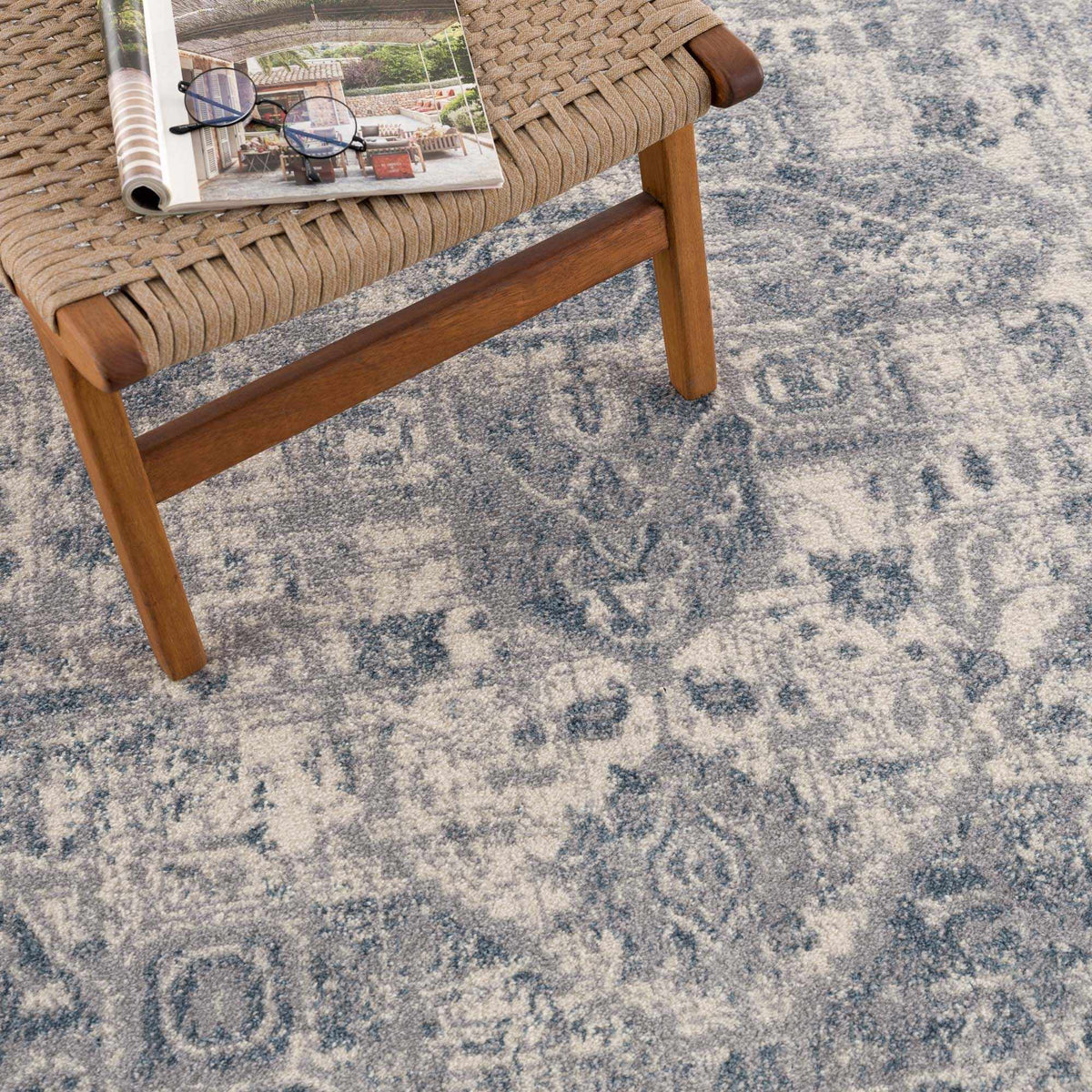 Gray and blue medallion area rug by Hauteloom featuring intricate patterns, displayed on a wooden floor in a styled room.