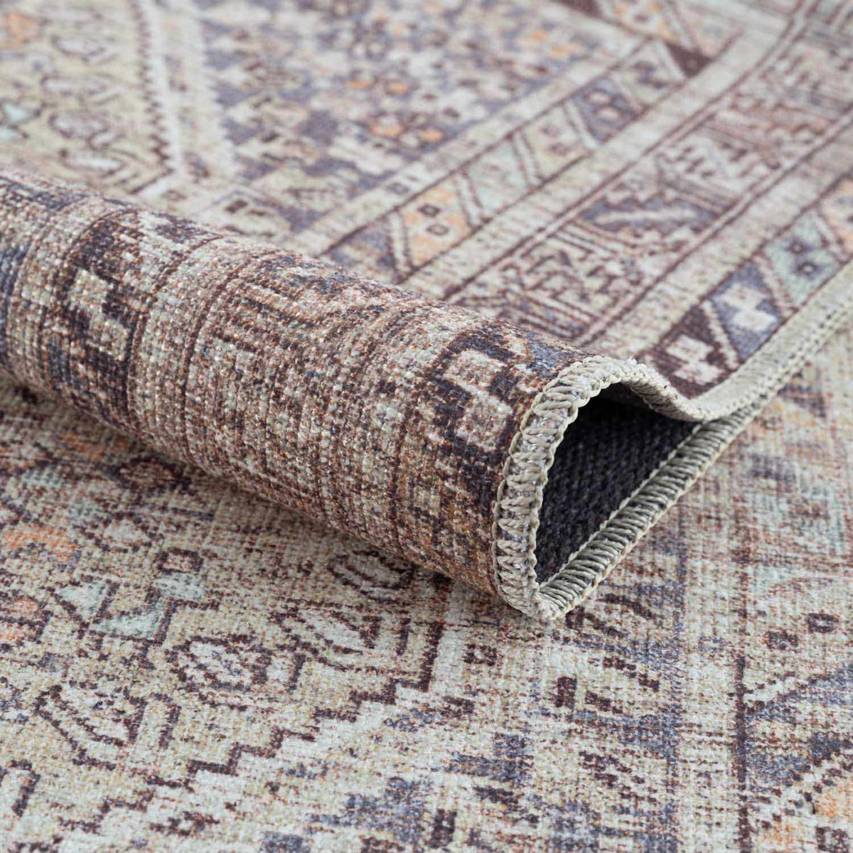 Folded Barny Tan Washable Area Rug from Boutique Rugs, showing soft textured fabric and neutral tan color.