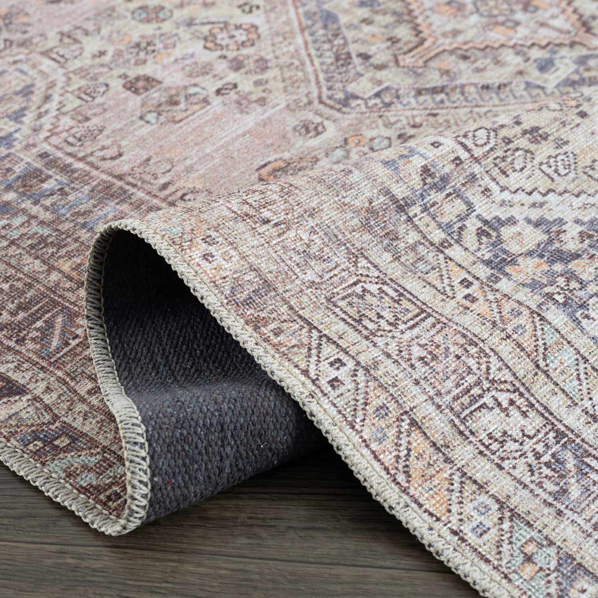 Folded Barny Tan washable area rug by Boutique Rugs, showing soft fabric texture and neutral tan color in a studio setting.