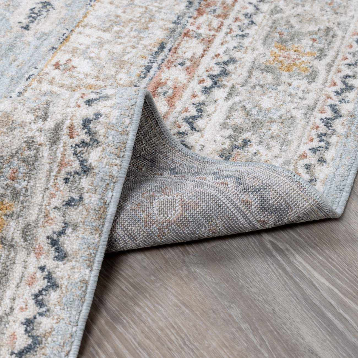 Gray and blue area rug by Boutique Rugs featuring a modern geometric pattern, shown folded on a neutral background.