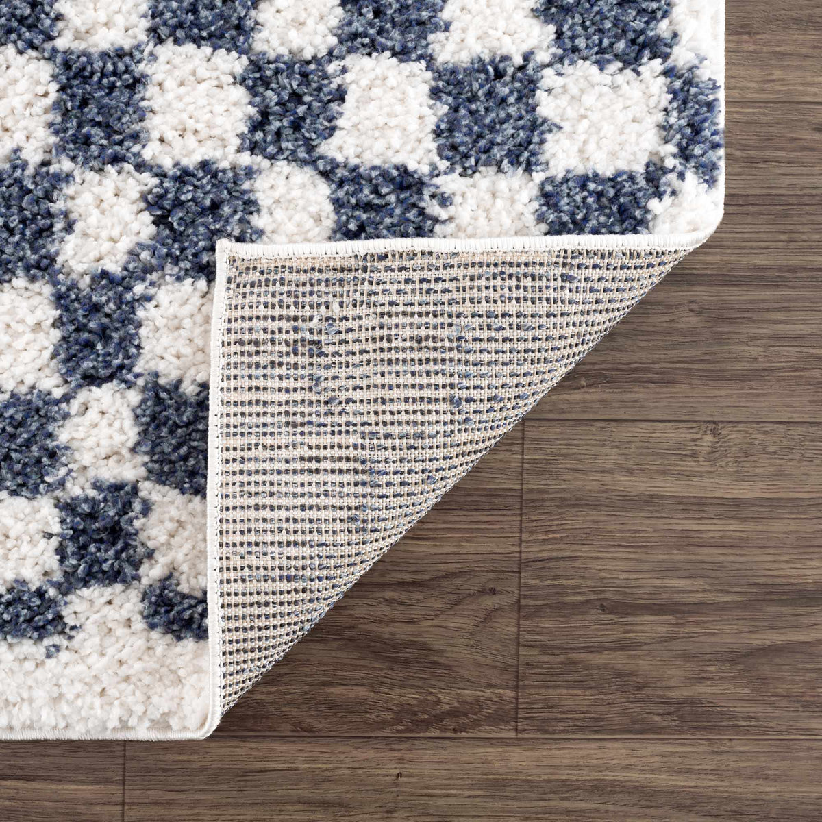 Blue and white checkered area rug by Boutique Rugs, folded to show its pattern and texture in a studio setting.
