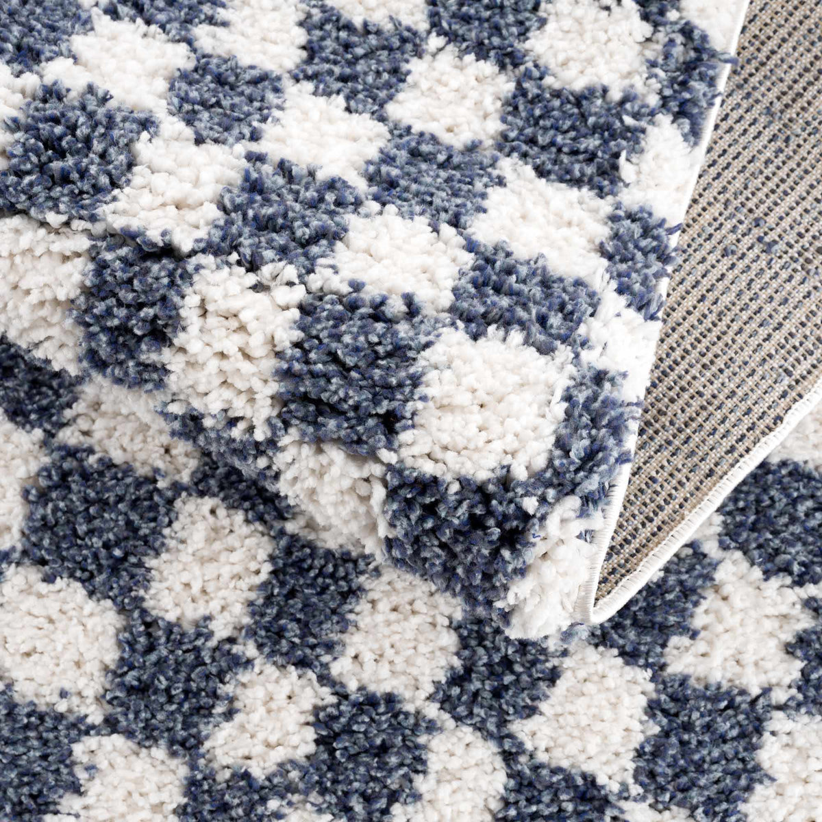 Blue and white checkered area rug from Boutique Rugs, folded to show the checkered pattern and textured fabric.