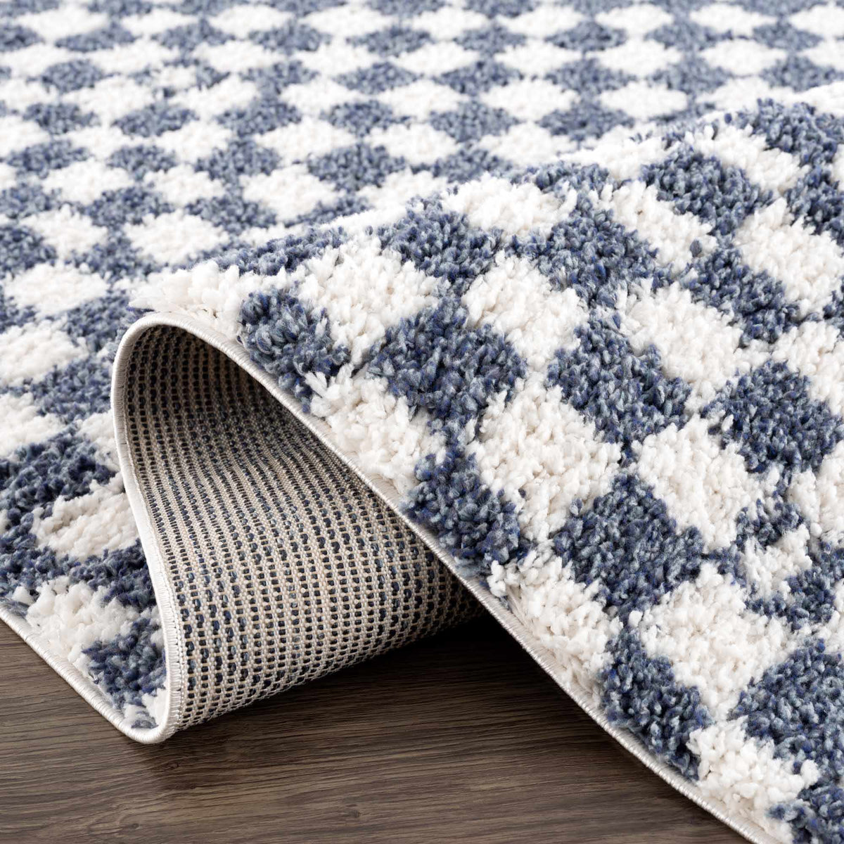 Blue and white checkered area rug from Boutique Rugs, folded on studio background showcasing its pattern and soft texture.