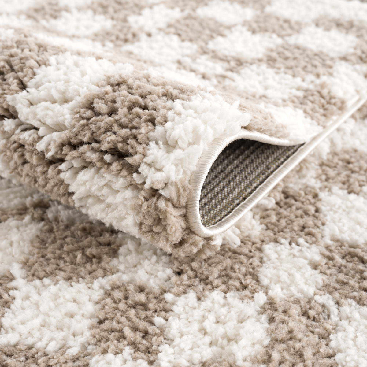 Taupe checkered shag rug by Boutique Rugs, folded to show plush texture and soft pile in a stylish geometric pattern.