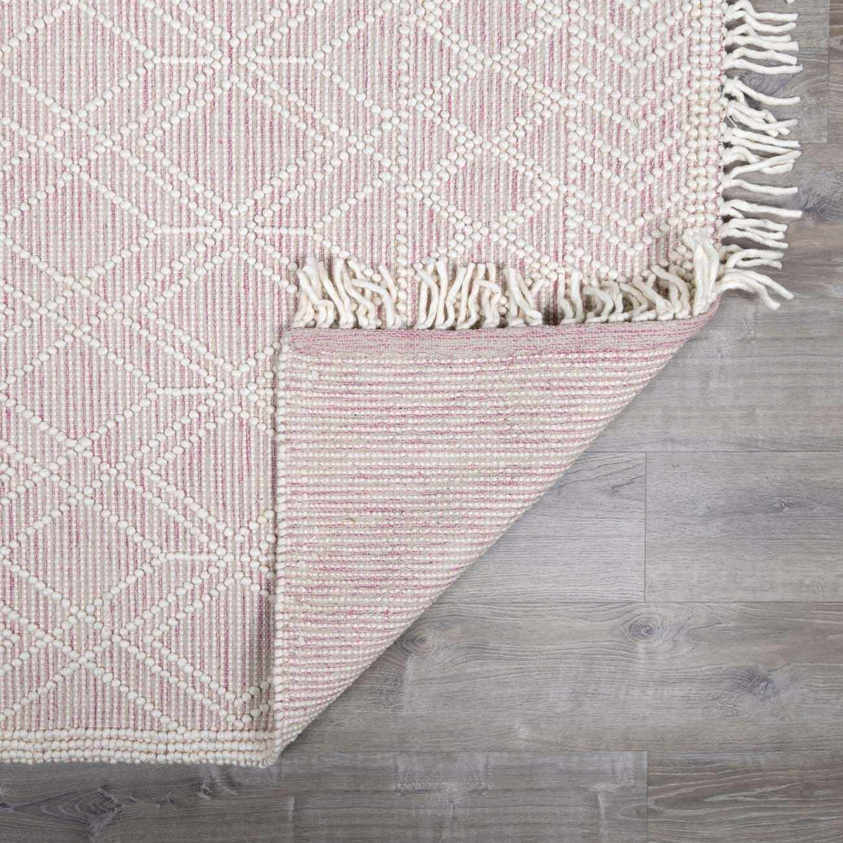 Soft pink wool rug from Boutique Rugs, shown folded with a textured surface, ideal for adding cozy warmth to living spaces.