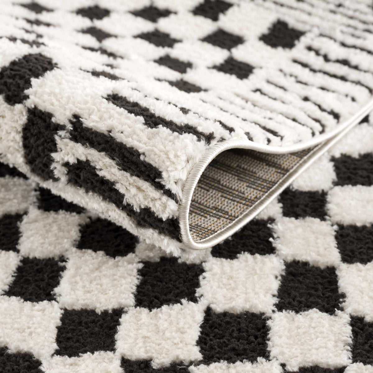 Black and white checkered area rug by Boutique Rugs, showcasing a folded section with a classic checkered pattern.