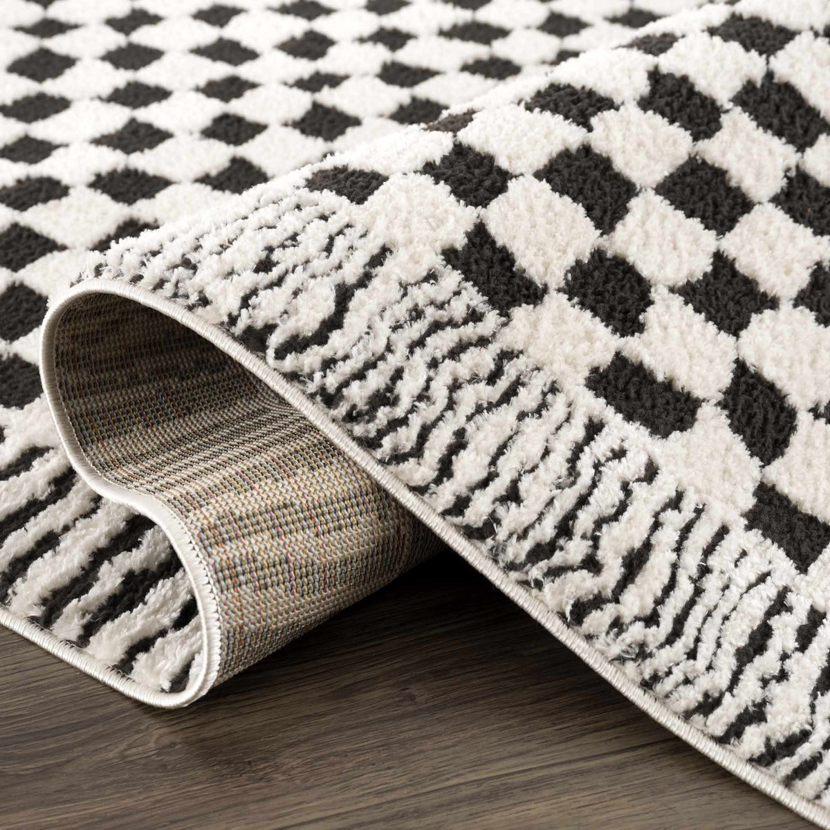 Black and white checkered area rug by Boutique Rugs, featuring a folded view showcasing its pattern and texture.