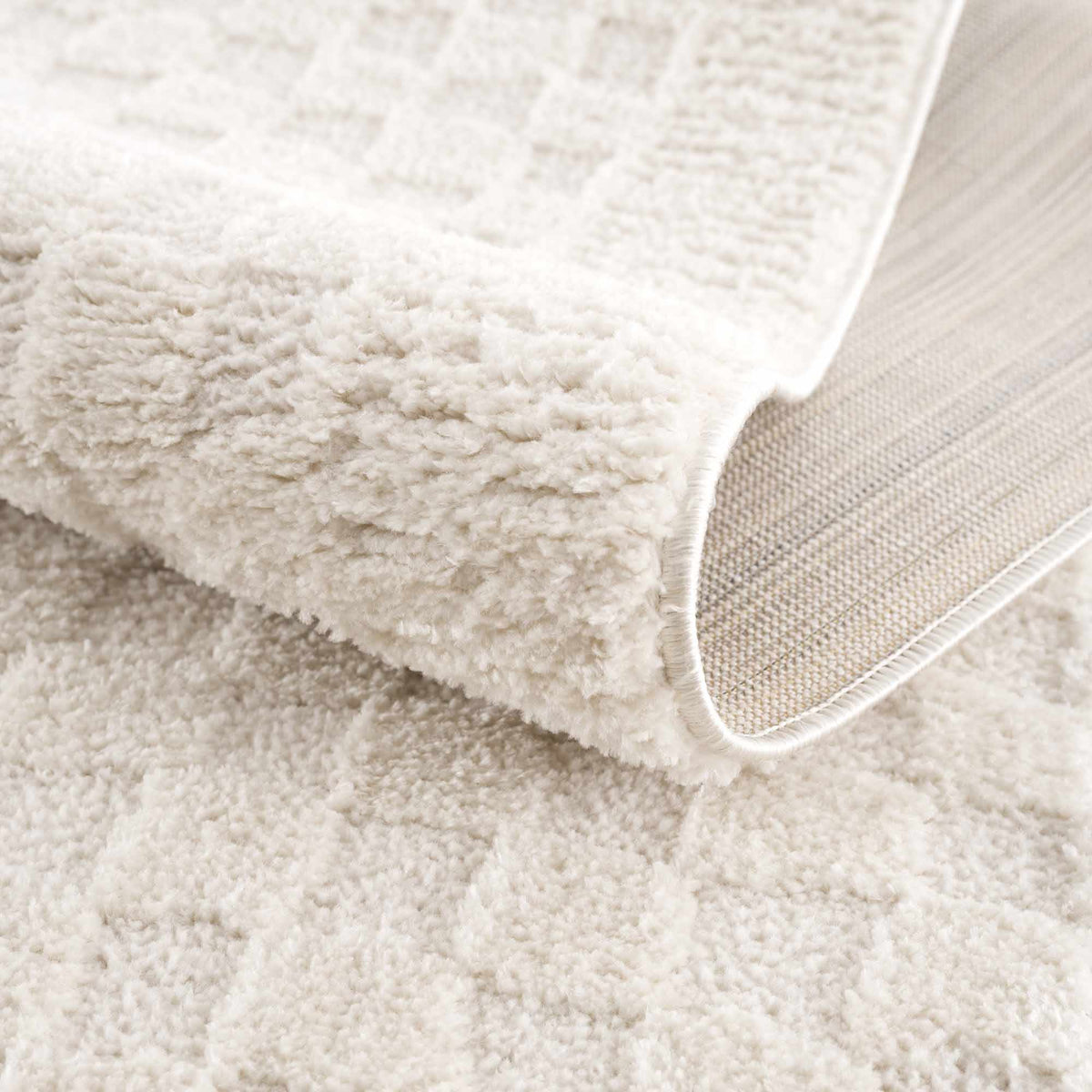 Folded ivory checkered area rug by Boutique Rugs, showcasing a soft, patterned design ideal for living rooms or bedrooms.