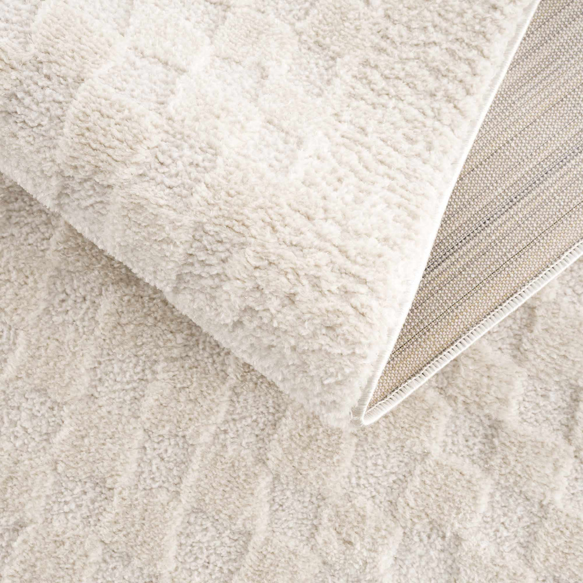 Ivory checkered area rug by Boutique Rugs, featuring a soft geometric pattern, shown folded on studio background.