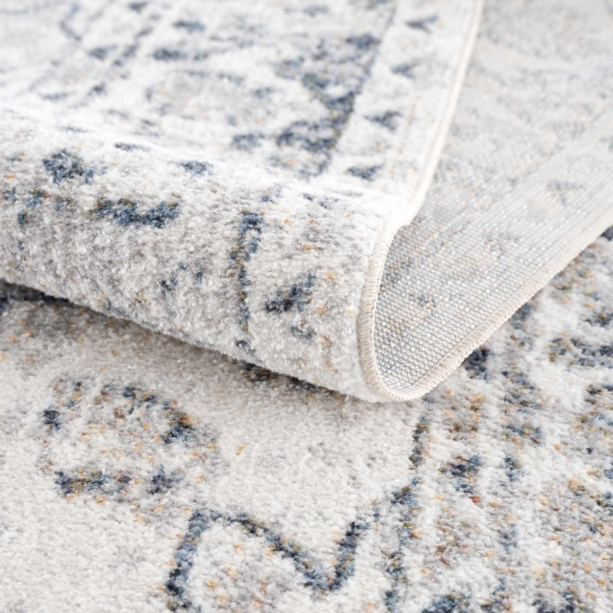 Folded Rudo Flat Pile Washable Rug by Boutique Rugs, showcasing its soft texture and neutral color in a modern home setting.