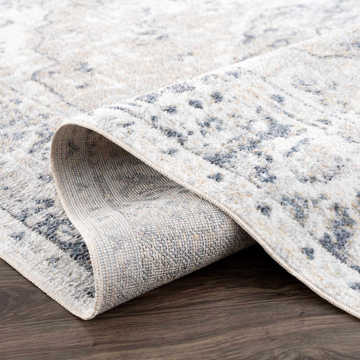 Folded Rudo Flat Pile Washable Rug by Boutique Rugs, showcasing its soft texture and neutral color in a studio setting.