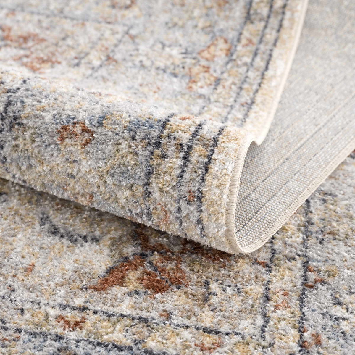 Folded Emke flat pile washable rug by Boutique Rugs, showing soft, textured fabric in neutral tones on a studio background.