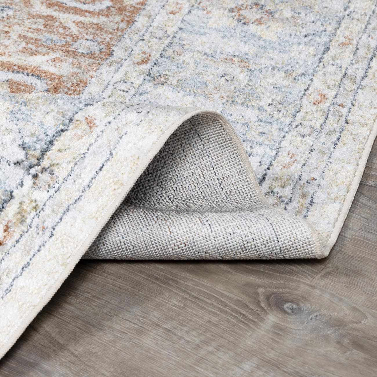 Folded Emke Flat Pile Washable Rug by Boutique Rugs, showcasing soft, durable fabric in a neutral color.