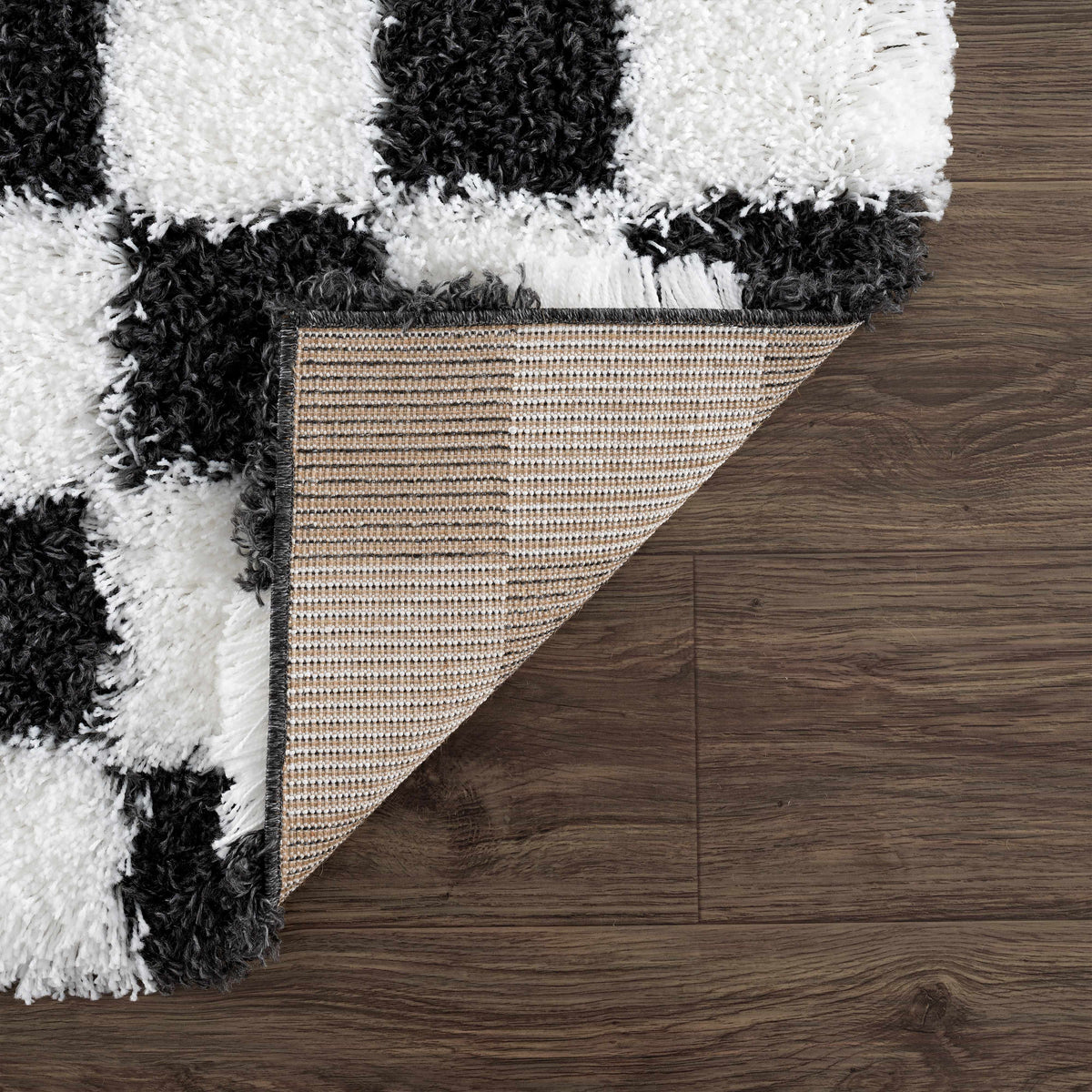 Black and white checkered area rug by Boutique Rugs, showing folded design and textured fabric in a studio setting.