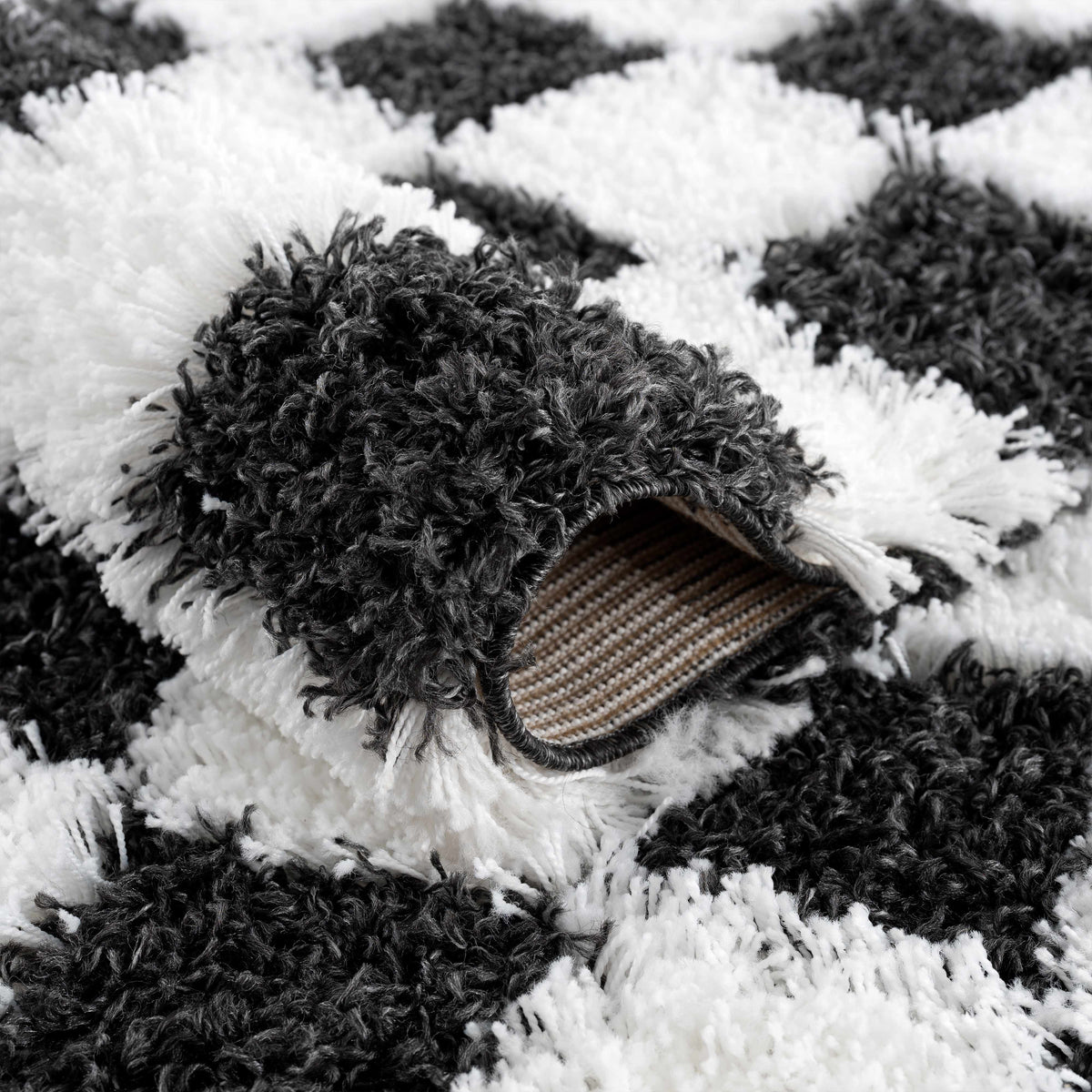 Black and white checkered area rug from Boutique Rugs, featuring a folded corner and modern geometric design.