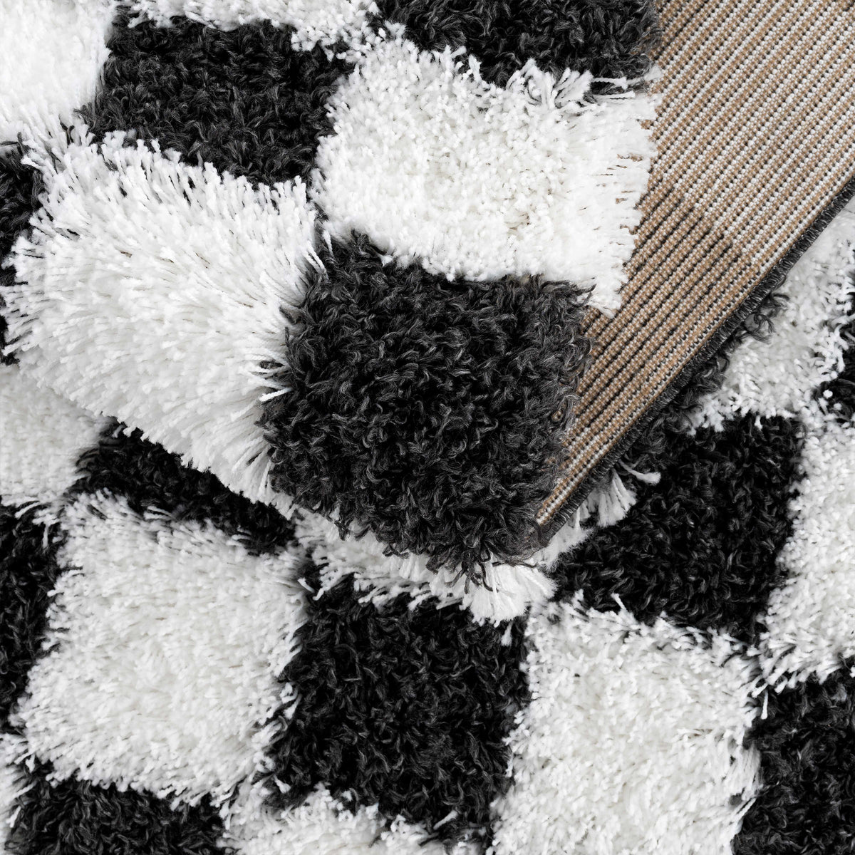 Black and white checkered area rug by Boutique Rugs, folded to show its pattern and texture in a studio setting.