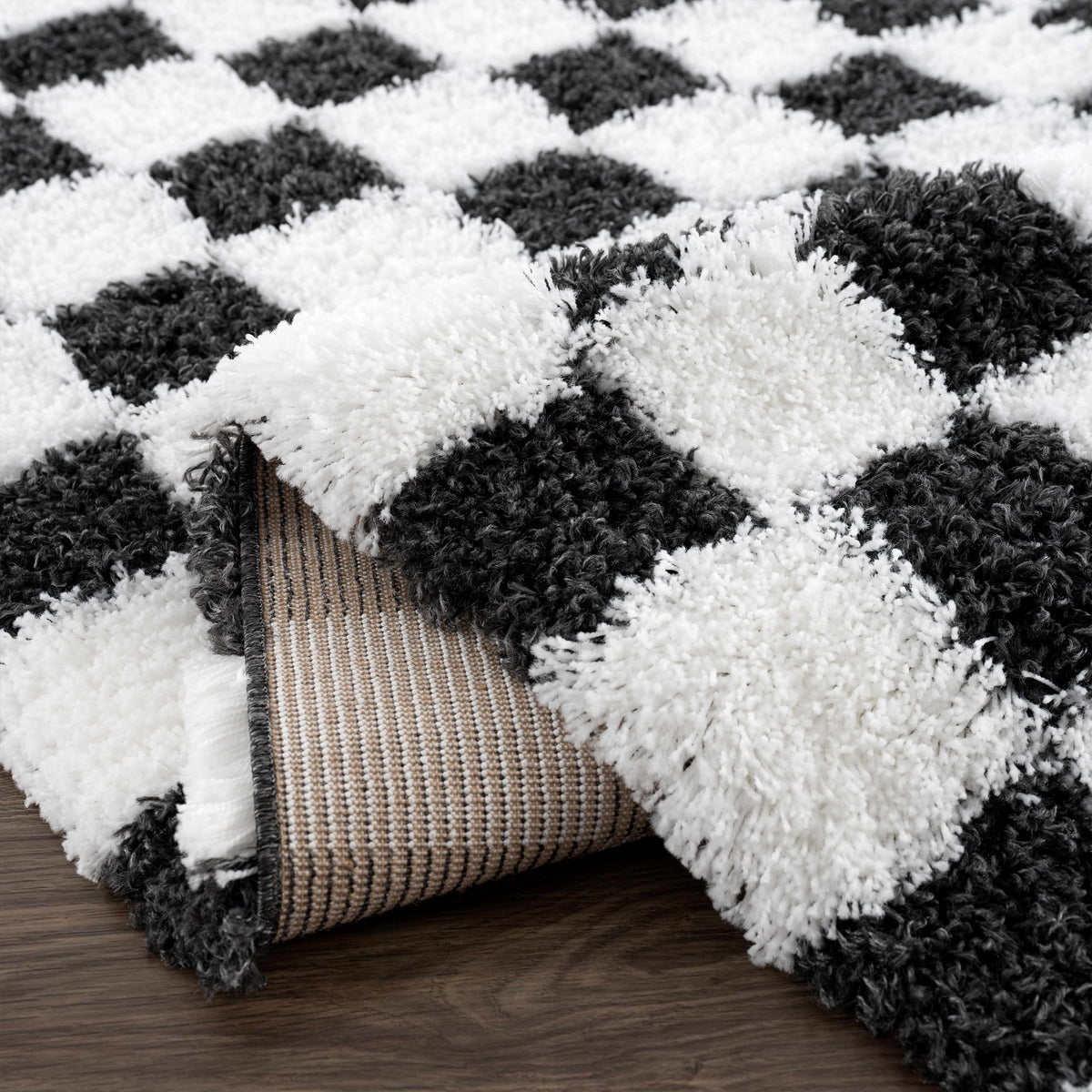 Black and white checkered area rug by Boutique Rugs, folded to show its pattern and texture on a neutral background.