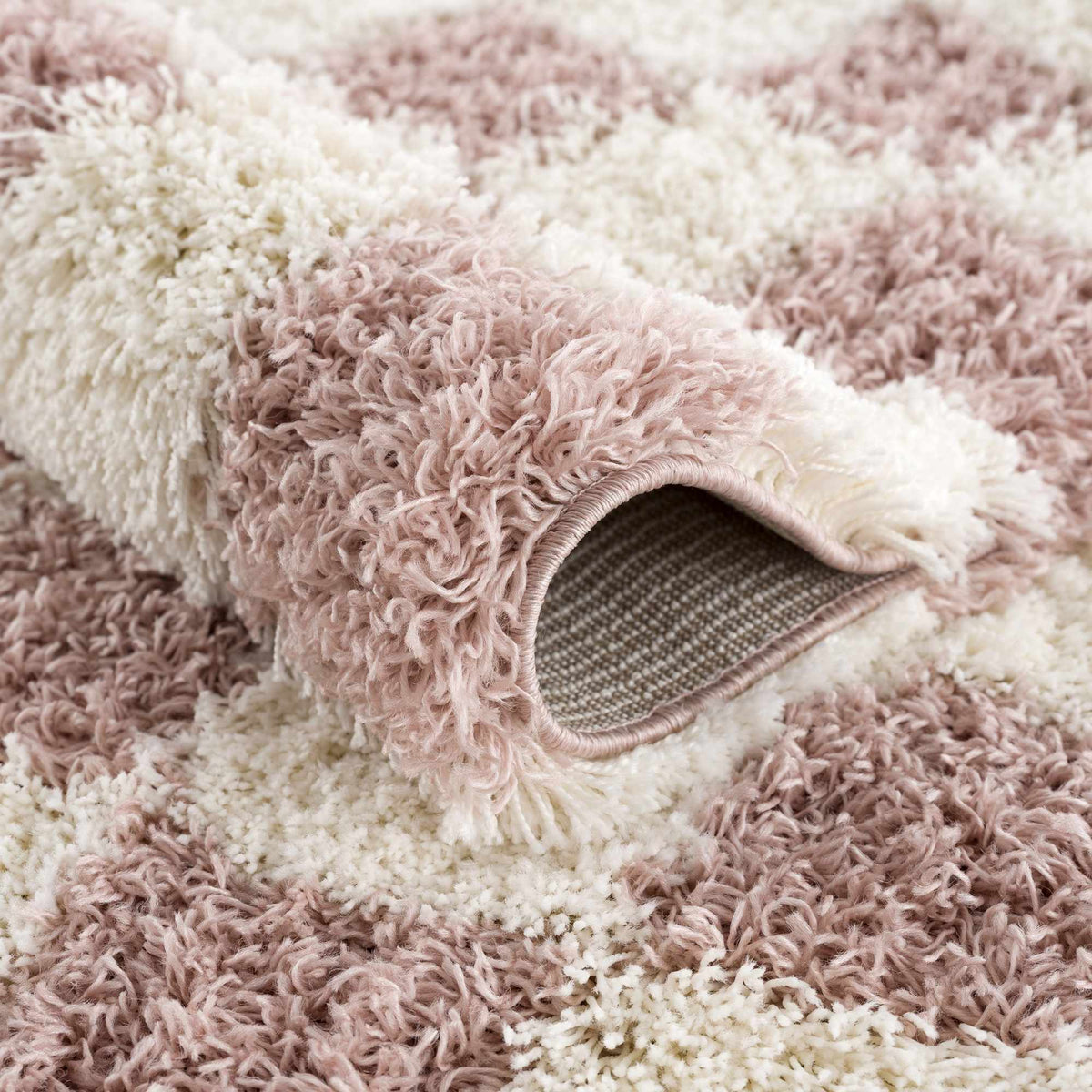 Pink checkered shag rug by Boutique Rugs, folded to showcase its soft, textured pile and vibrant pattern.