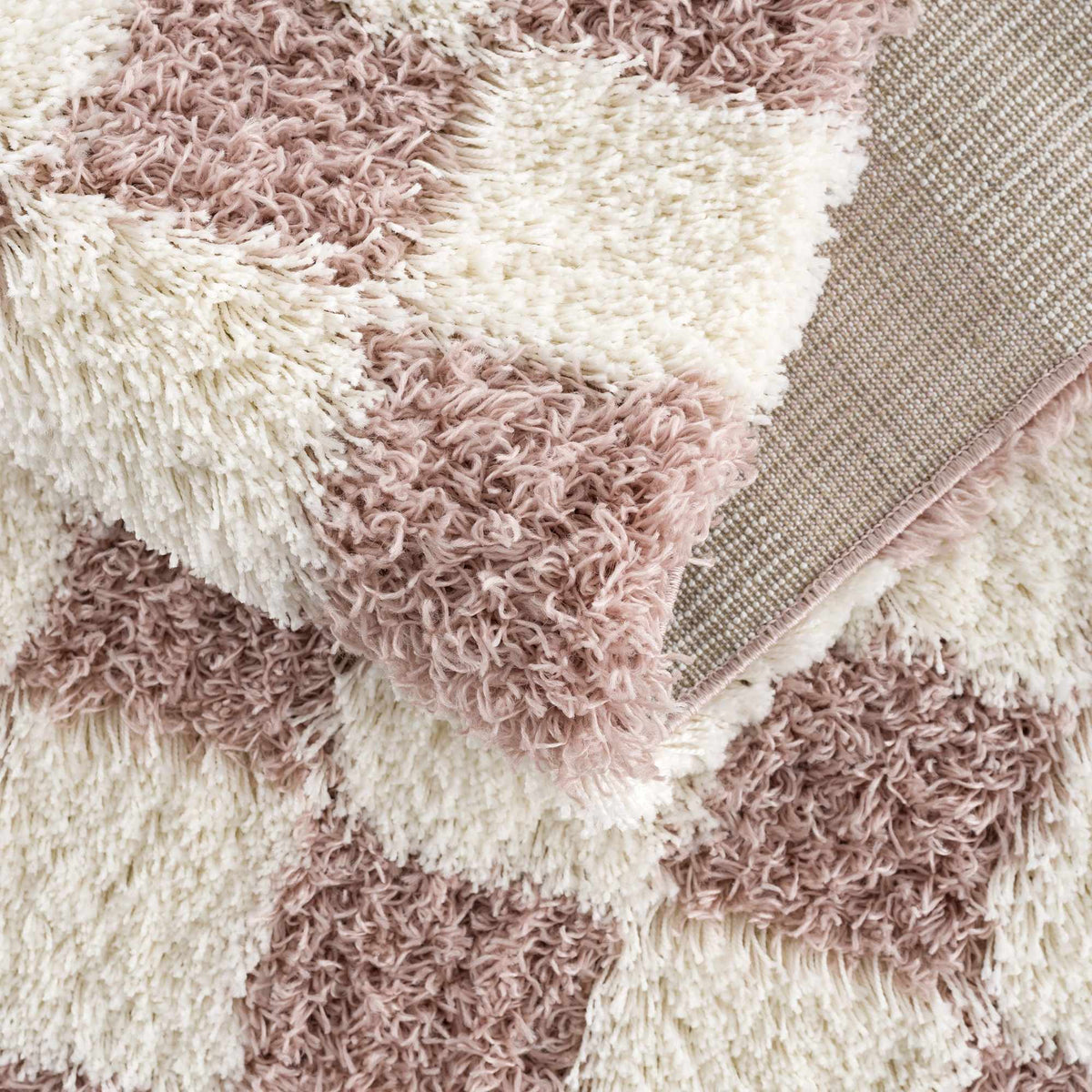 Pink checkered shag rug from Boutique Rugs, folded to show soft, plush texture and vibrant pattern.