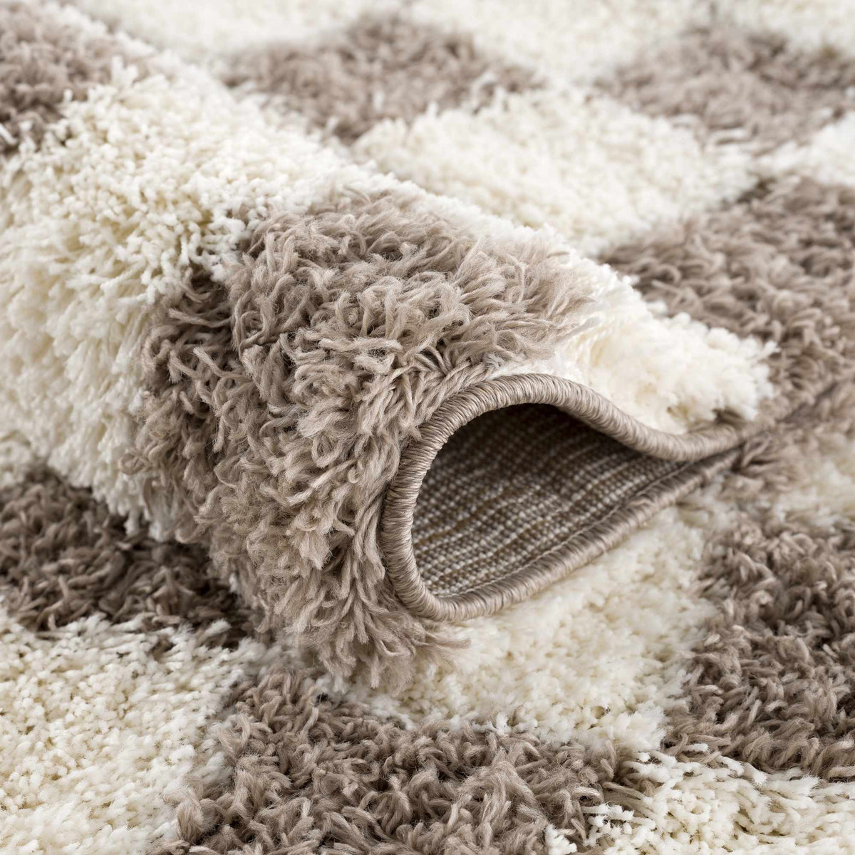 Brown checkered Boutique Rugs area rug with a folded corner, showcasing a stylish pattern and soft texture.