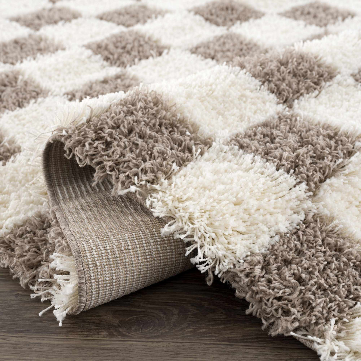 Folded Atira brown checkered area rug by Boutique Rugs shown in a studio setting, highlighting its pattern and texture.