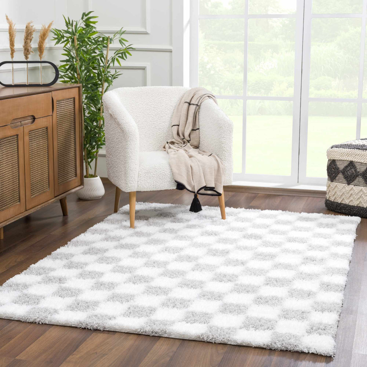 Gray checkered area rug by Boutique Rugs, shown in a cozy room setting with furniture and decor.