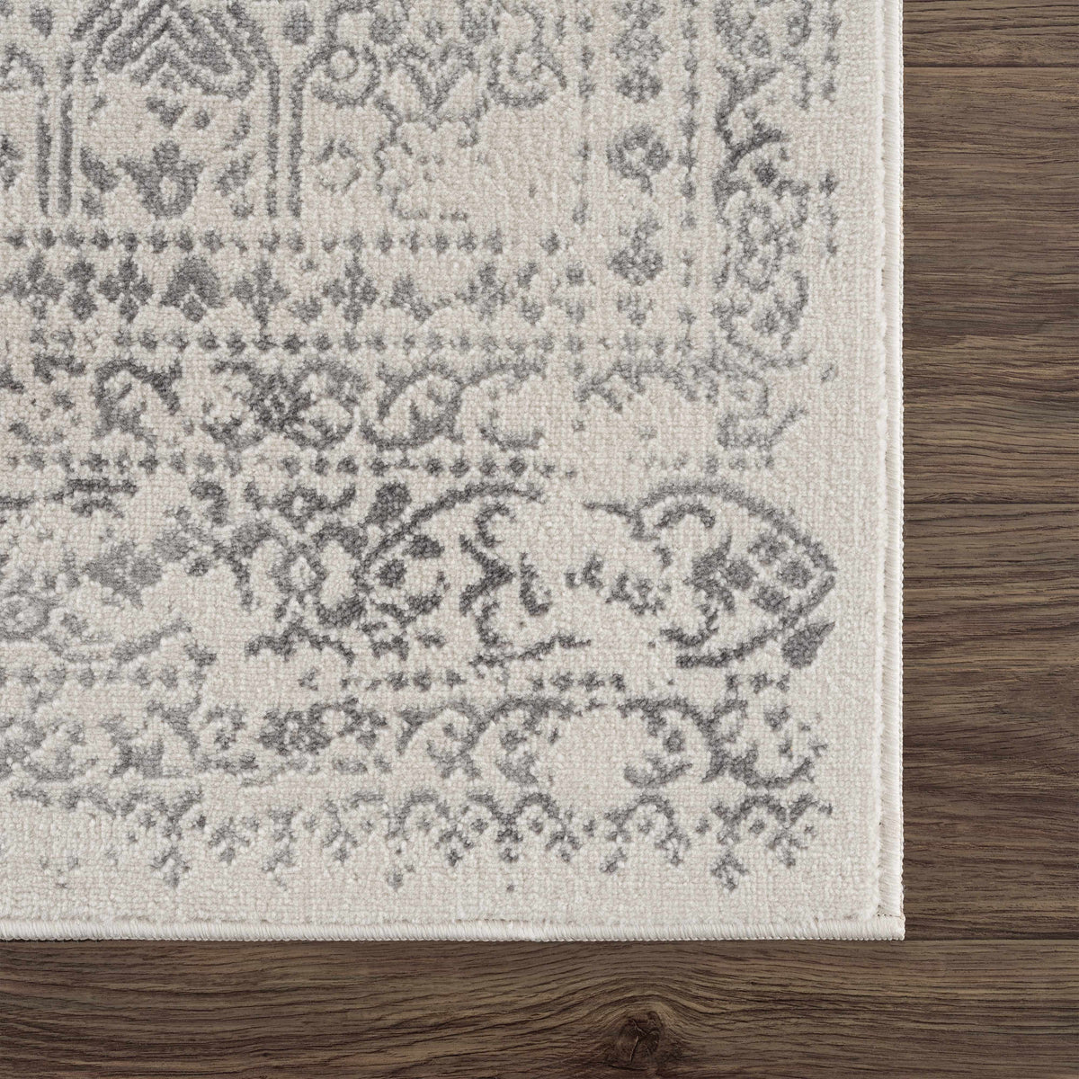 Hauteloom Michie area rug featuring a modern geometric pattern in neutral tones, shown draped in the corner of a room.