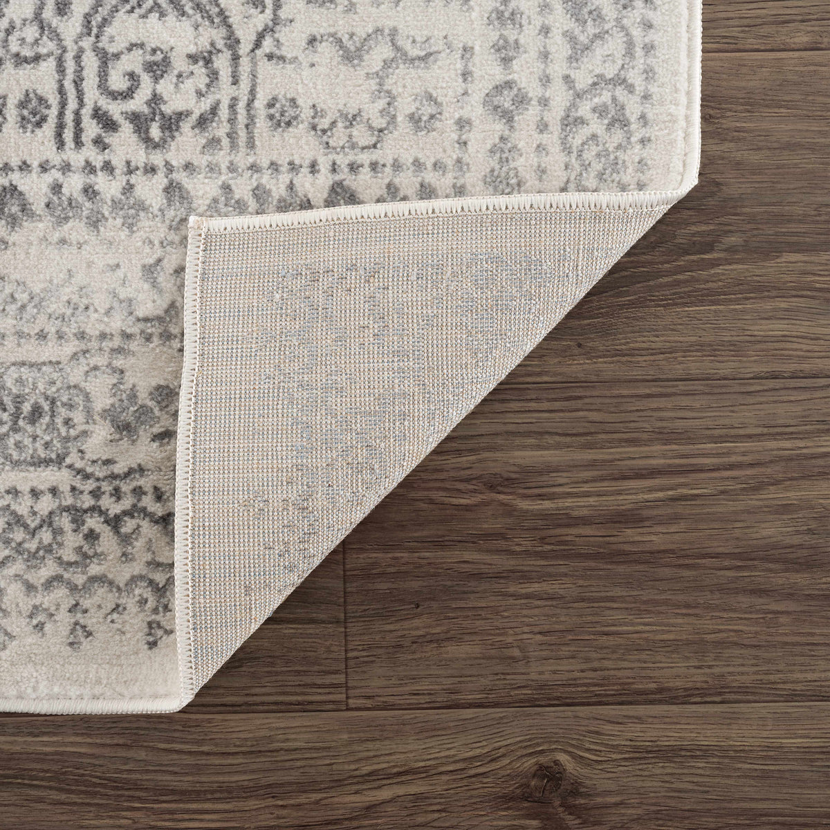 Hauteloom Michie area rug with intricate patterns in neutral tones, shown folded with detailed design visible.