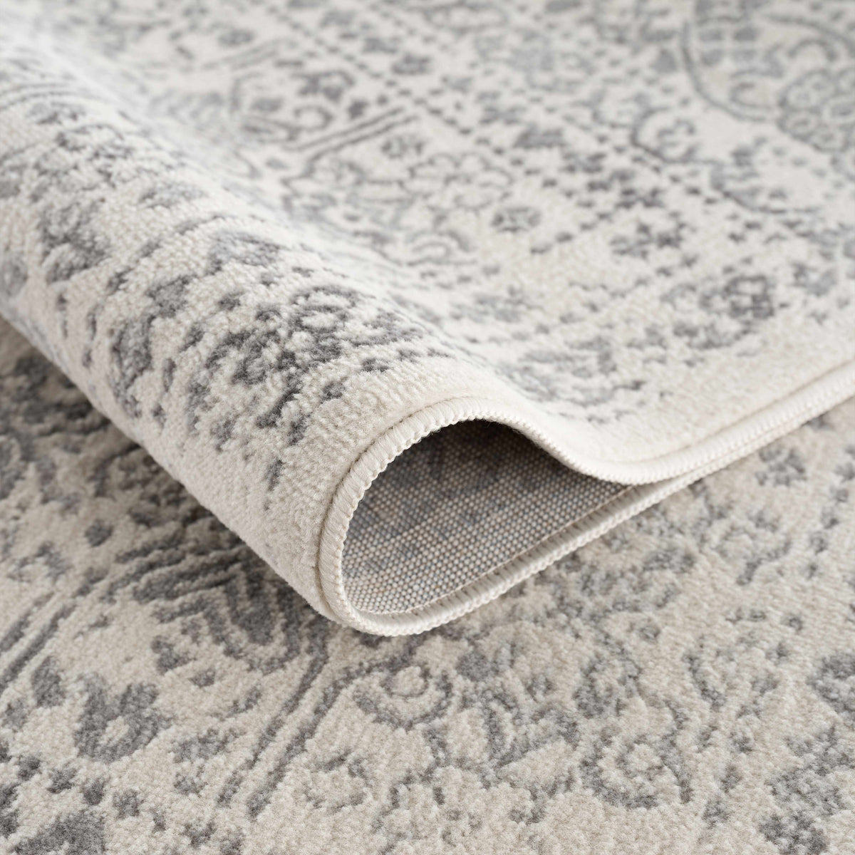 Hauteloom Michie area rug with geometric pattern in neutral tones, shown folded on a white background.